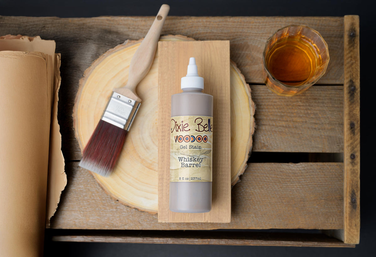 Bottle of Whiskey Barrel VooDoo Gel Stain with a brush and glass on a wooden surface