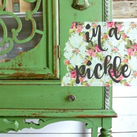 Green distressed cabinet with a floral sign reading 'in a pickle' on a white background