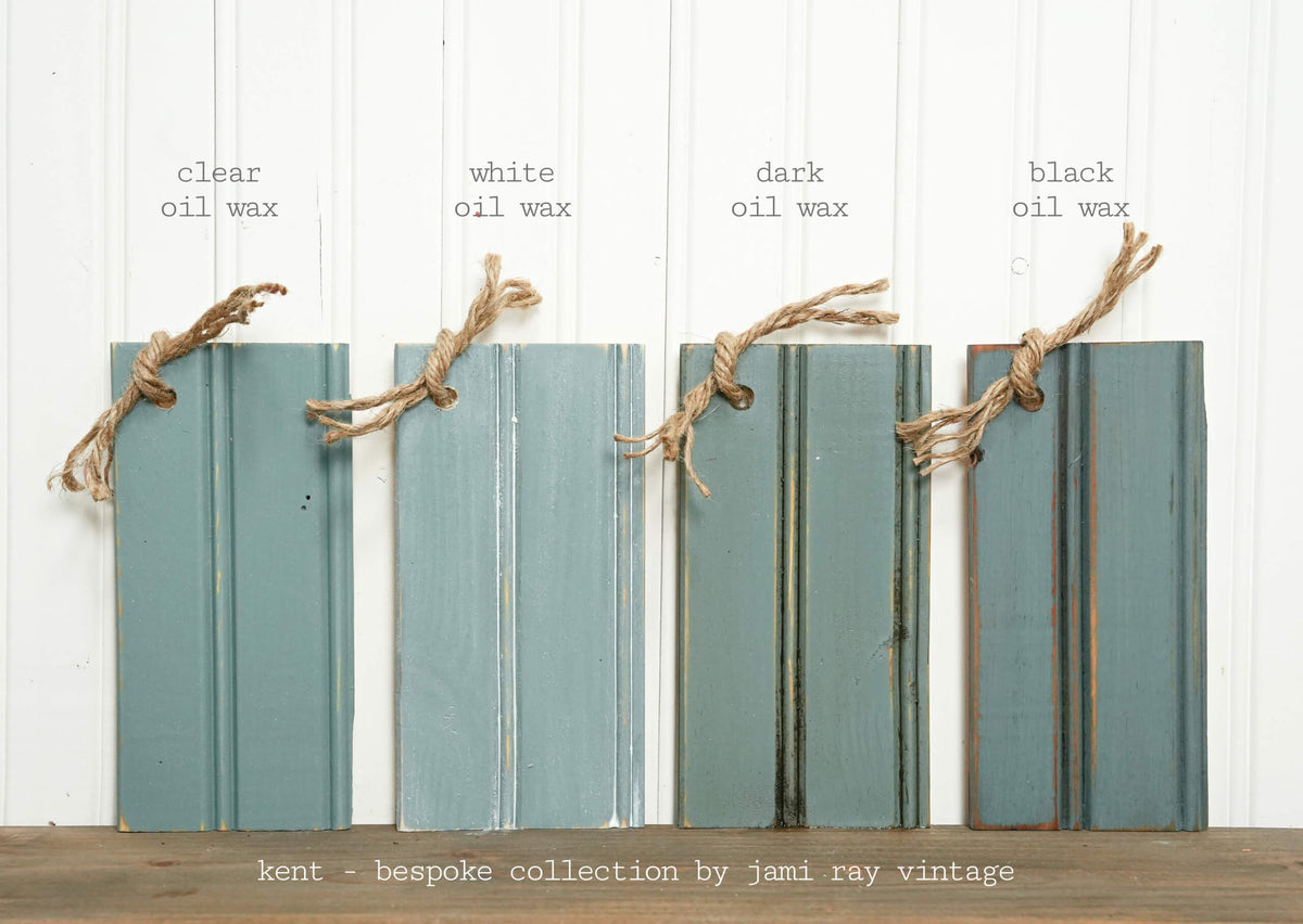 Four wooden planks with different oil wax finishes on a white background, labeled 'clear', 'white', 'dark', and 'black'.