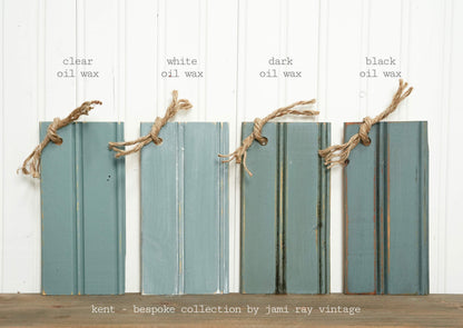 Four wooden planks with different oil wax finishes on a white background, labeled 'clear', 'white', 'dark', and 'black'.