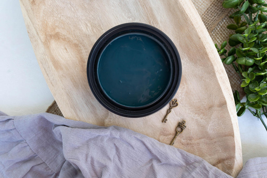 London Blue Terra Clay Paint, placed on a light wood board with a lavender cloth and small decorative keys nearby.