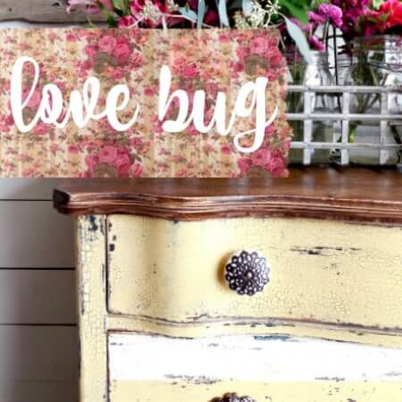 Decorative sign with 'love bug' text on a floral background above a distressed wooden surface.