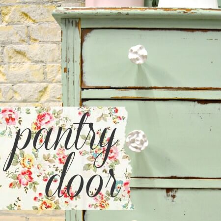 A distressed mint green wooden dresser with white knobs, next to a floral sign that reads 'pantry door' in black script.