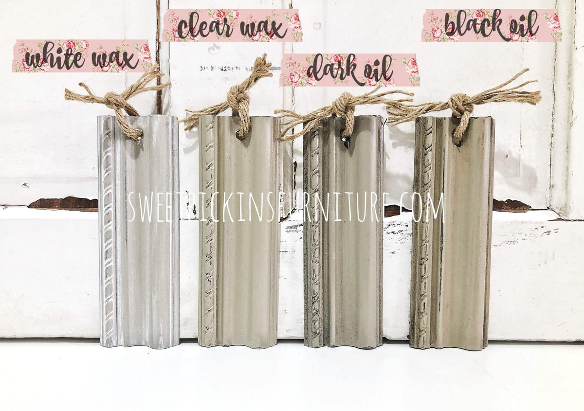 Set of wooden finish samples with labels for white wax, clear wax, dark oil, and black oil on a white background.