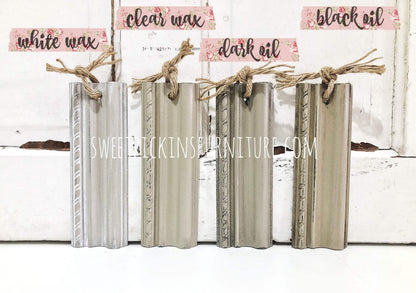 Set of wooden finish samples with labels for white wax, clear wax, dark oil, and black oil on a white background.