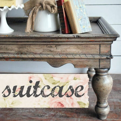 Wooden suitcase with floral design and 'suitcase' text on a wooden surface.