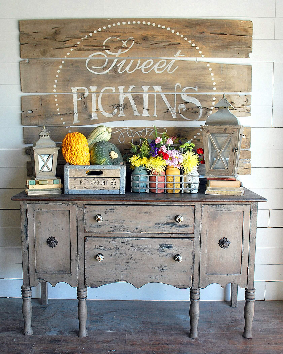 Decorative wooden sideboard with 'Sweet Pickins' sign and autumn-themed decor.