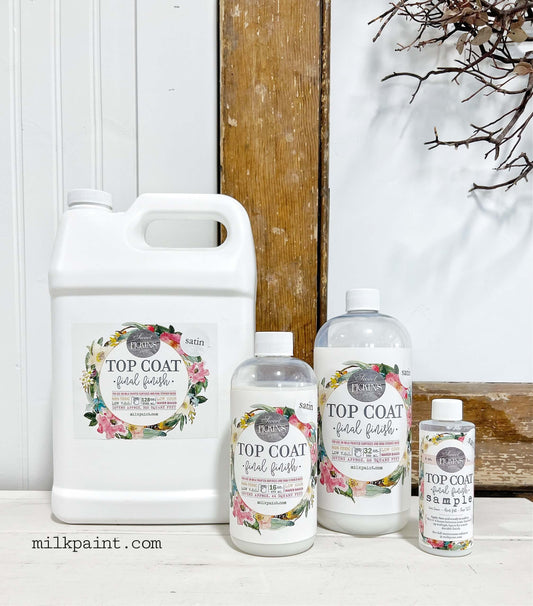 Set of Sweet Pickins Top Coat Final Finishes bottles on a wooden surface with a white background.